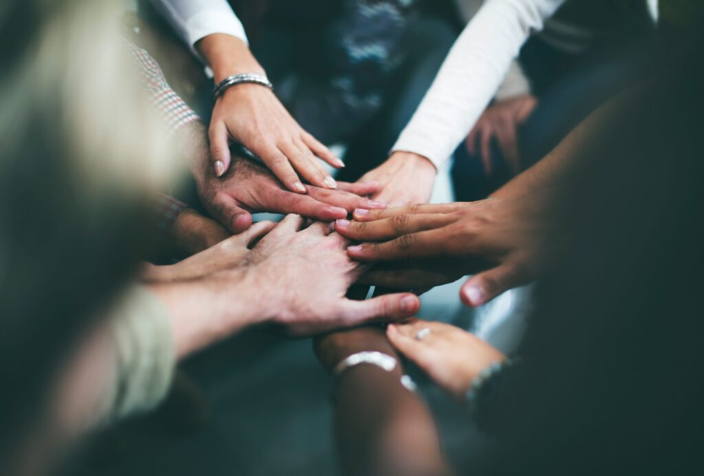 Close up of group huddle, with diverse group of people's hands on top of each other