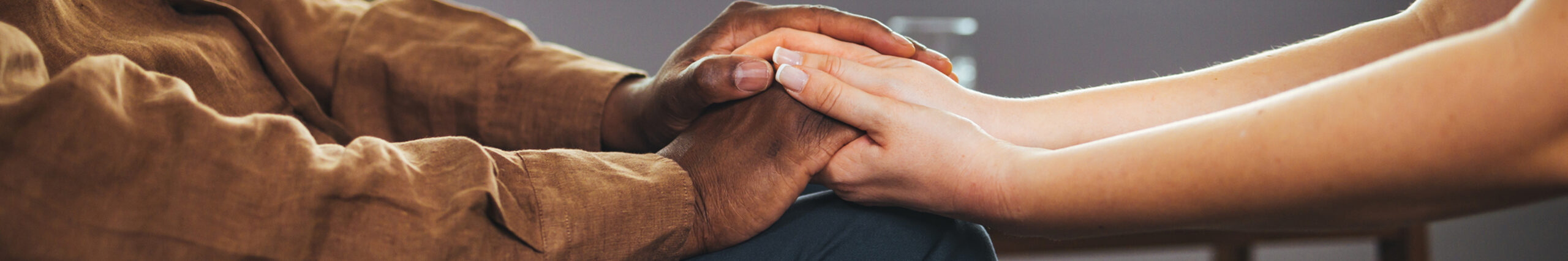 Closeup of one person's hands extended across a table holding another person's hands