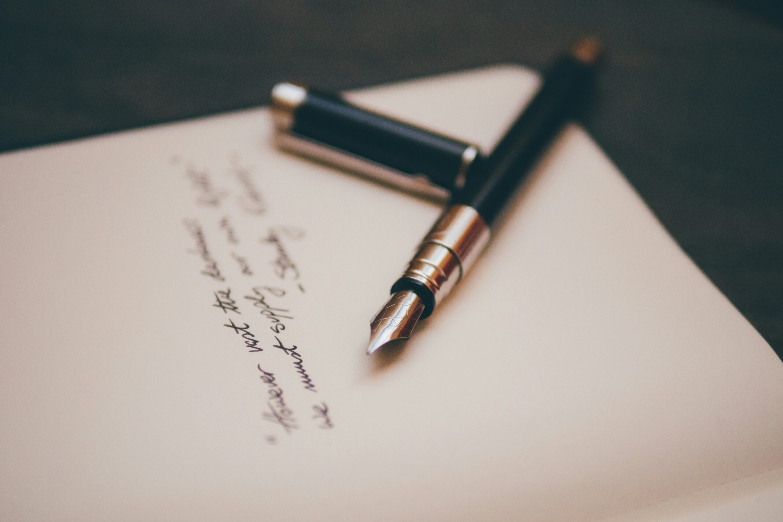 A handwritten note, with a calligraphy pen and the cap on top of the page.
