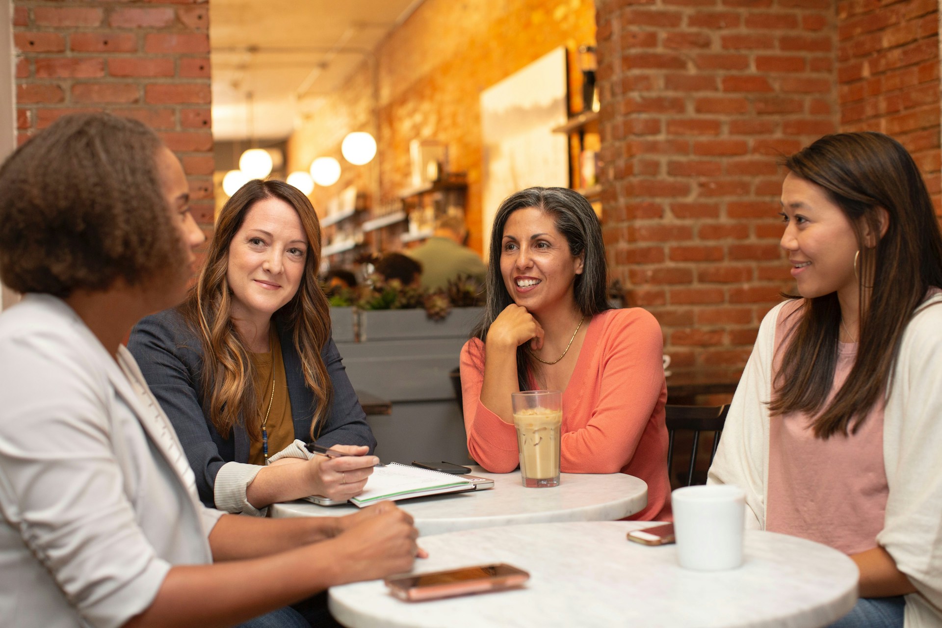 A diverse group of women sitting around a table in coversation
