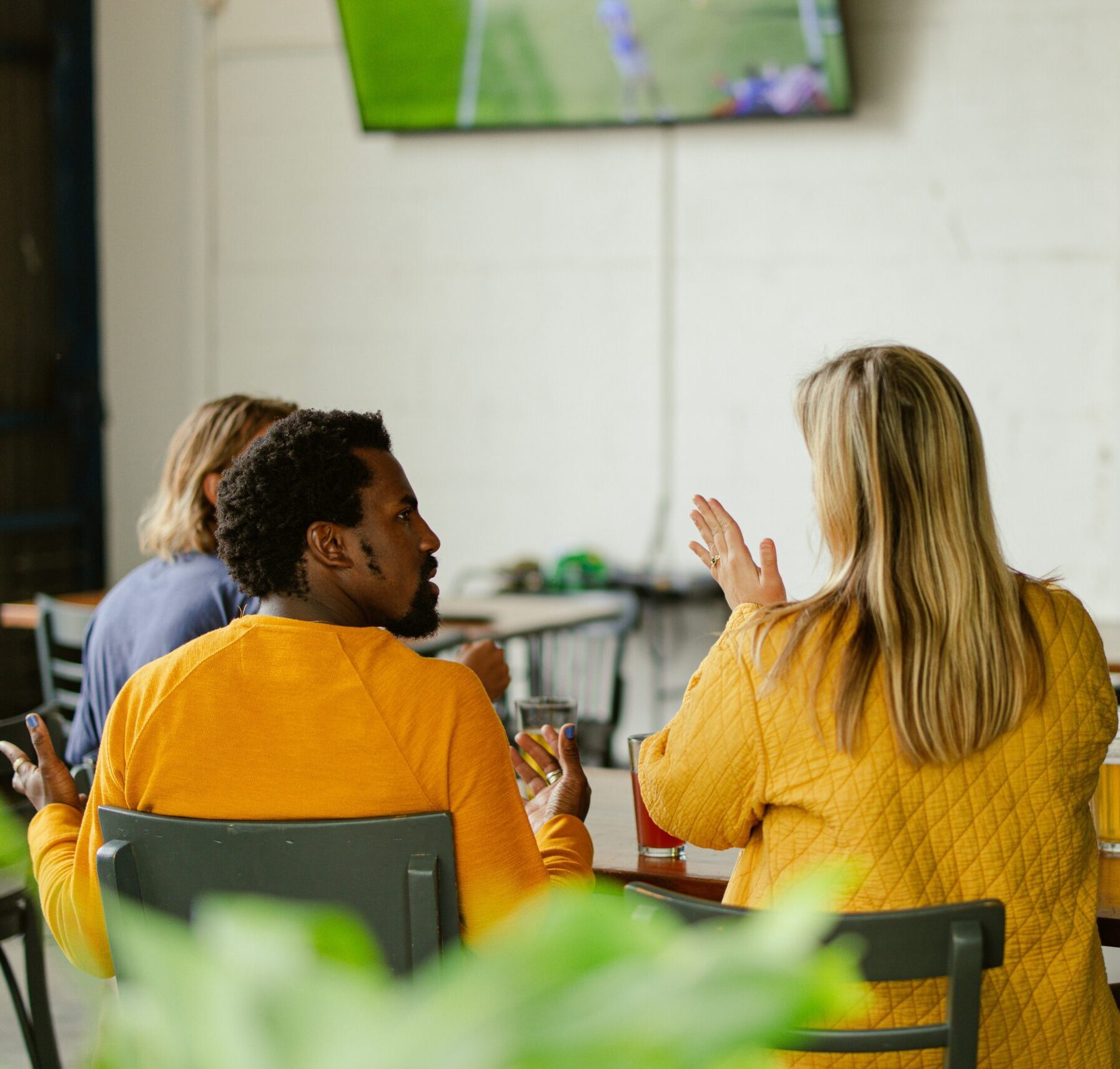 A diverse group of people having a conversation around a table in a cafe.