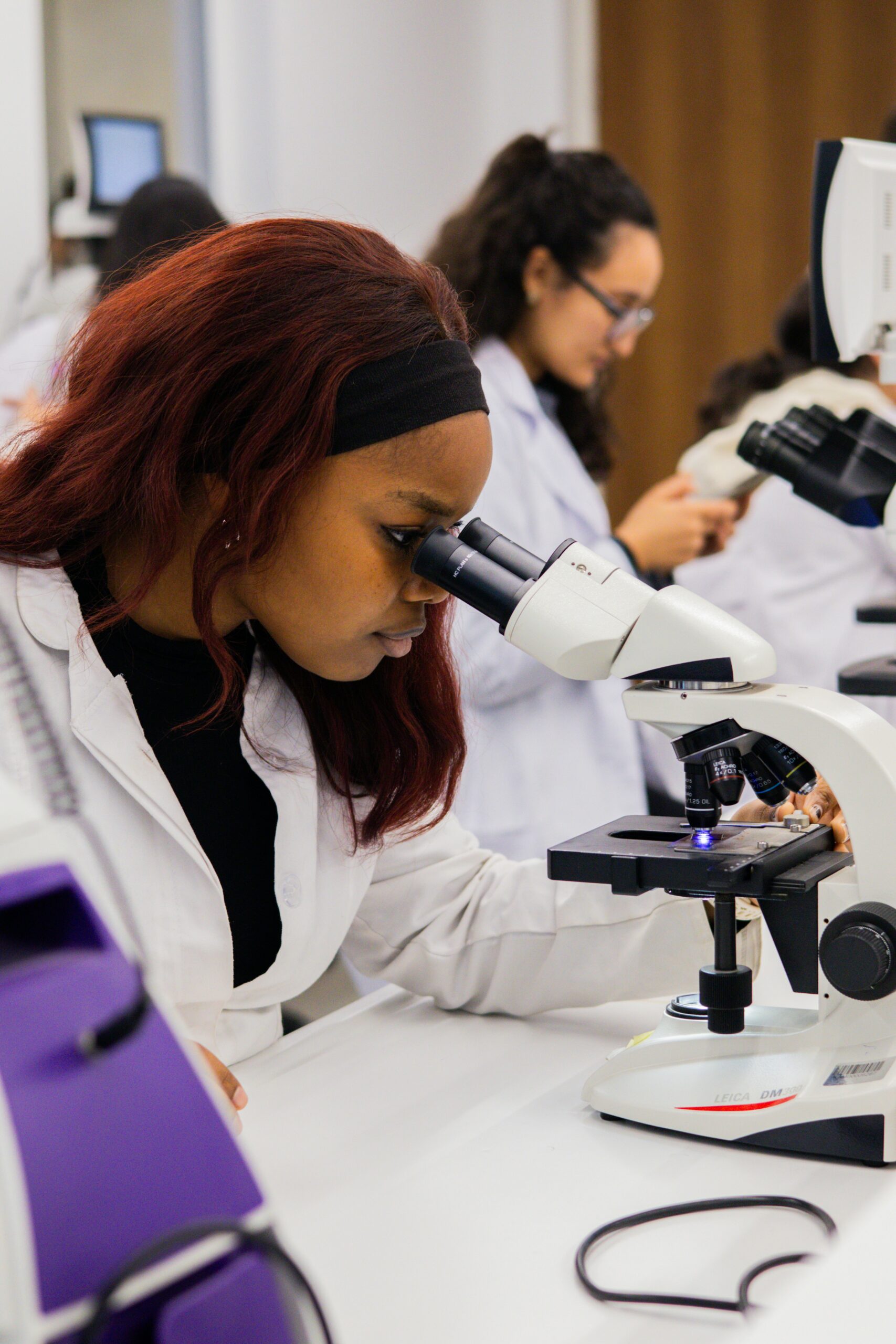 A female scientist looks through a microscope in a scientific lab.