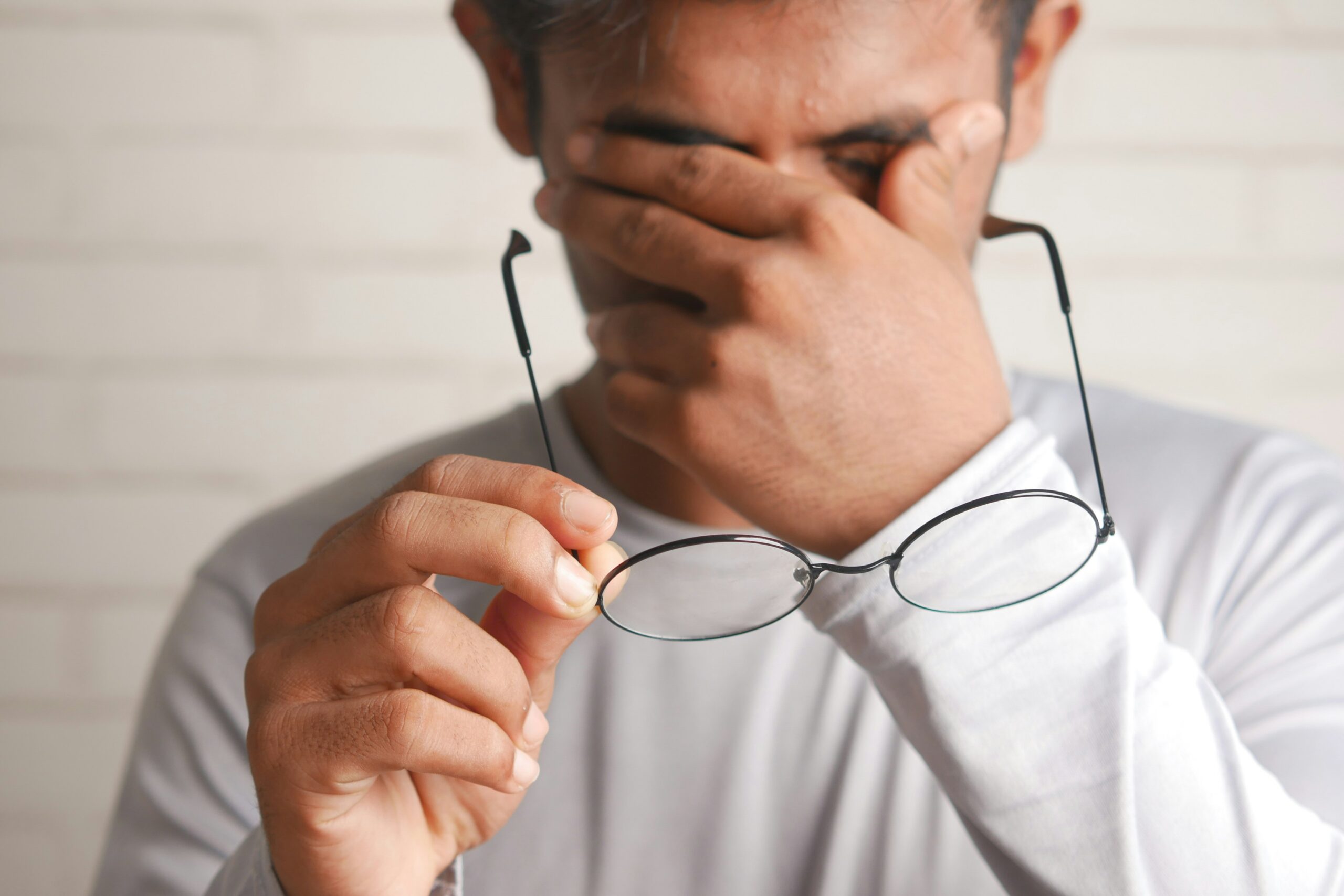 Man removing glasses and rubbing eyes