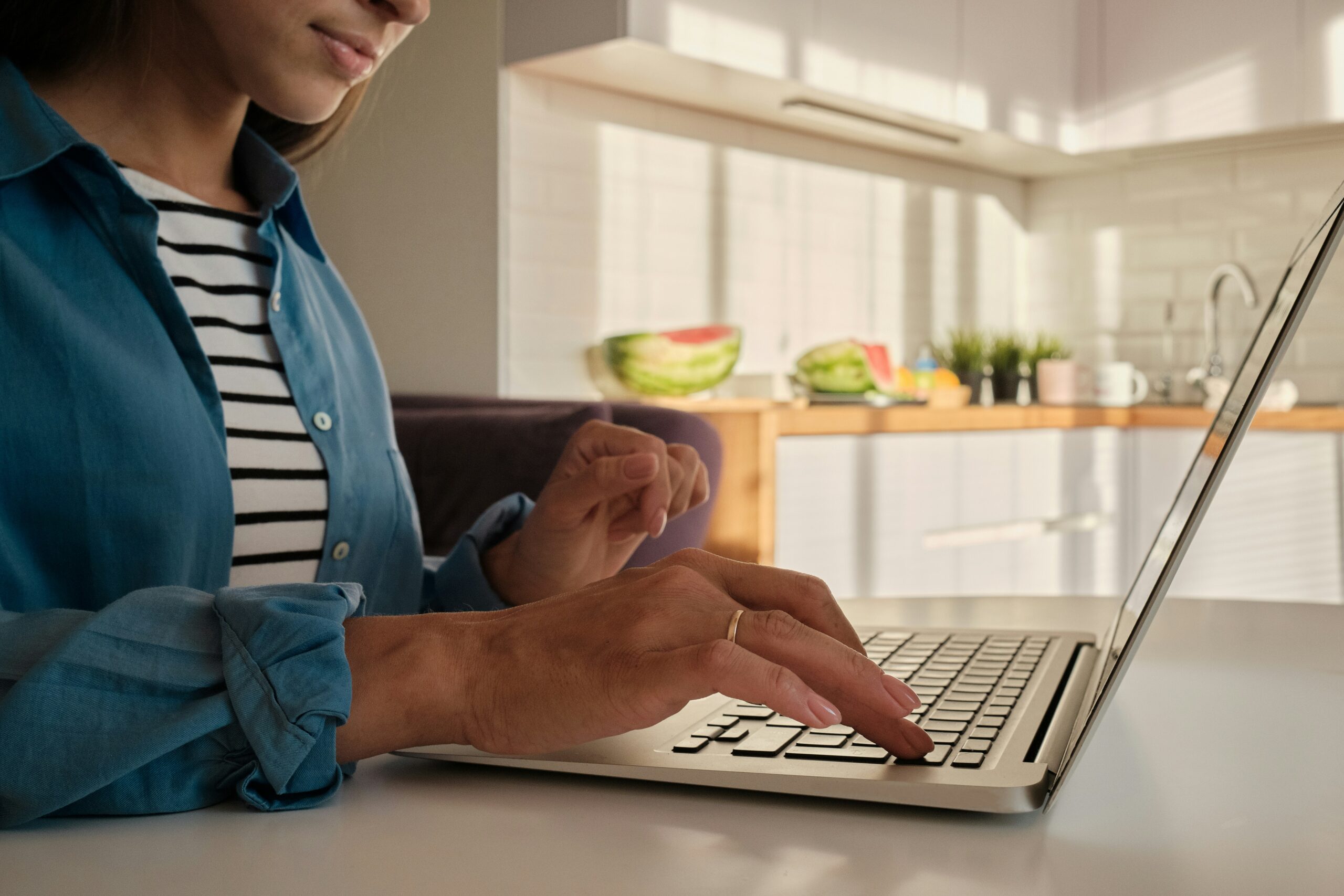 Woman typing on laptop in her kitchen