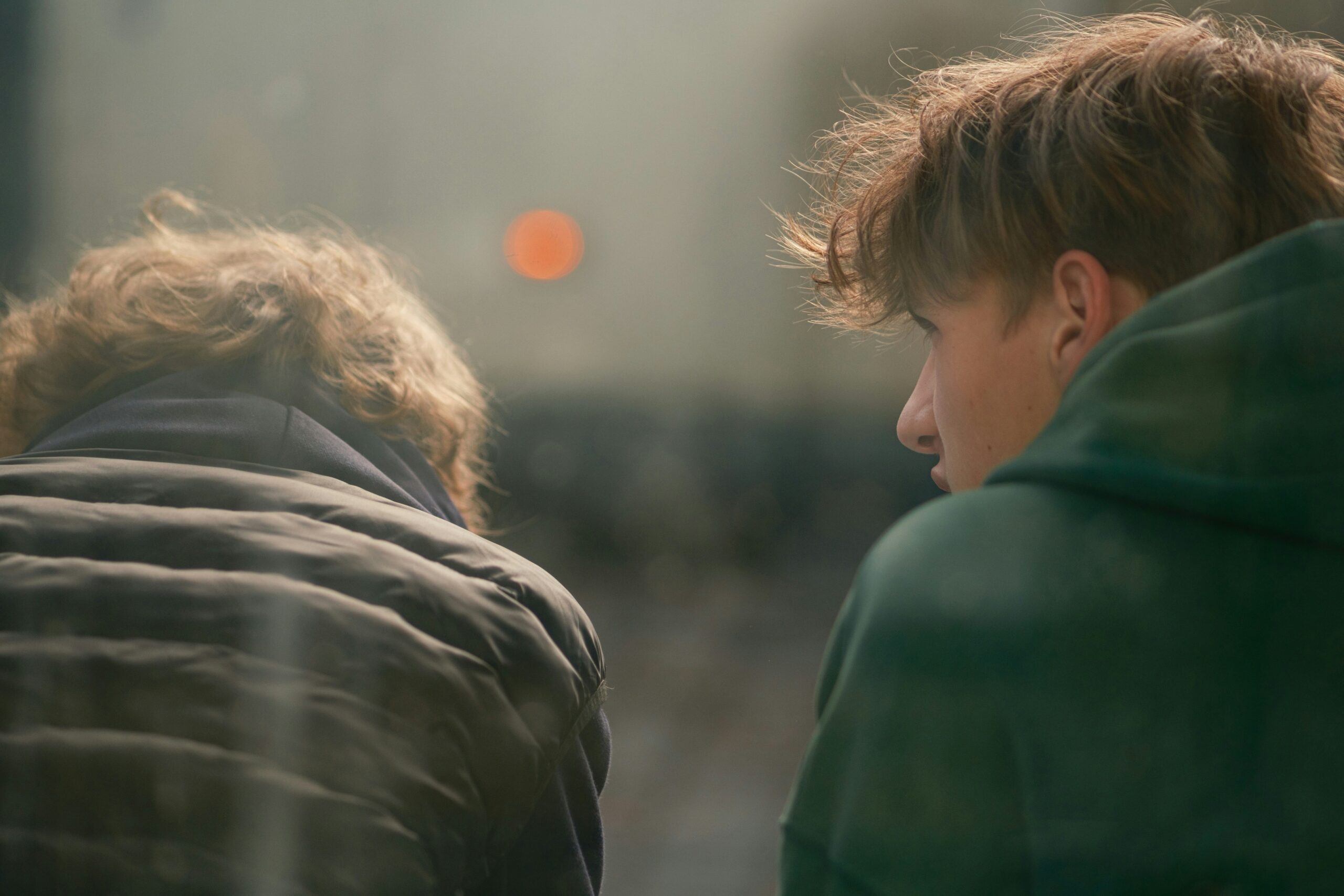 A back view of two teens sitting and talking closely