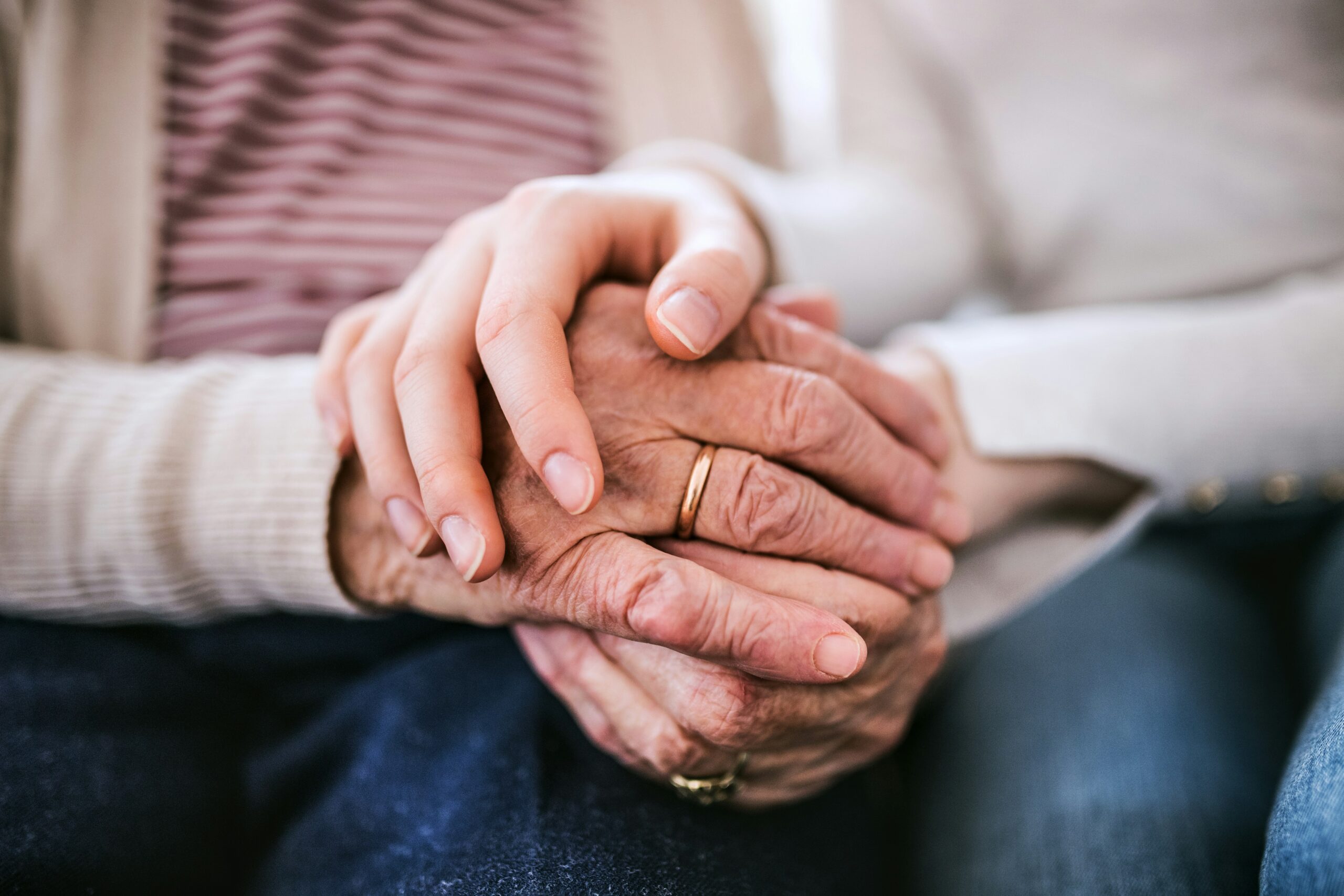 A senior holding the hands of a younger person.