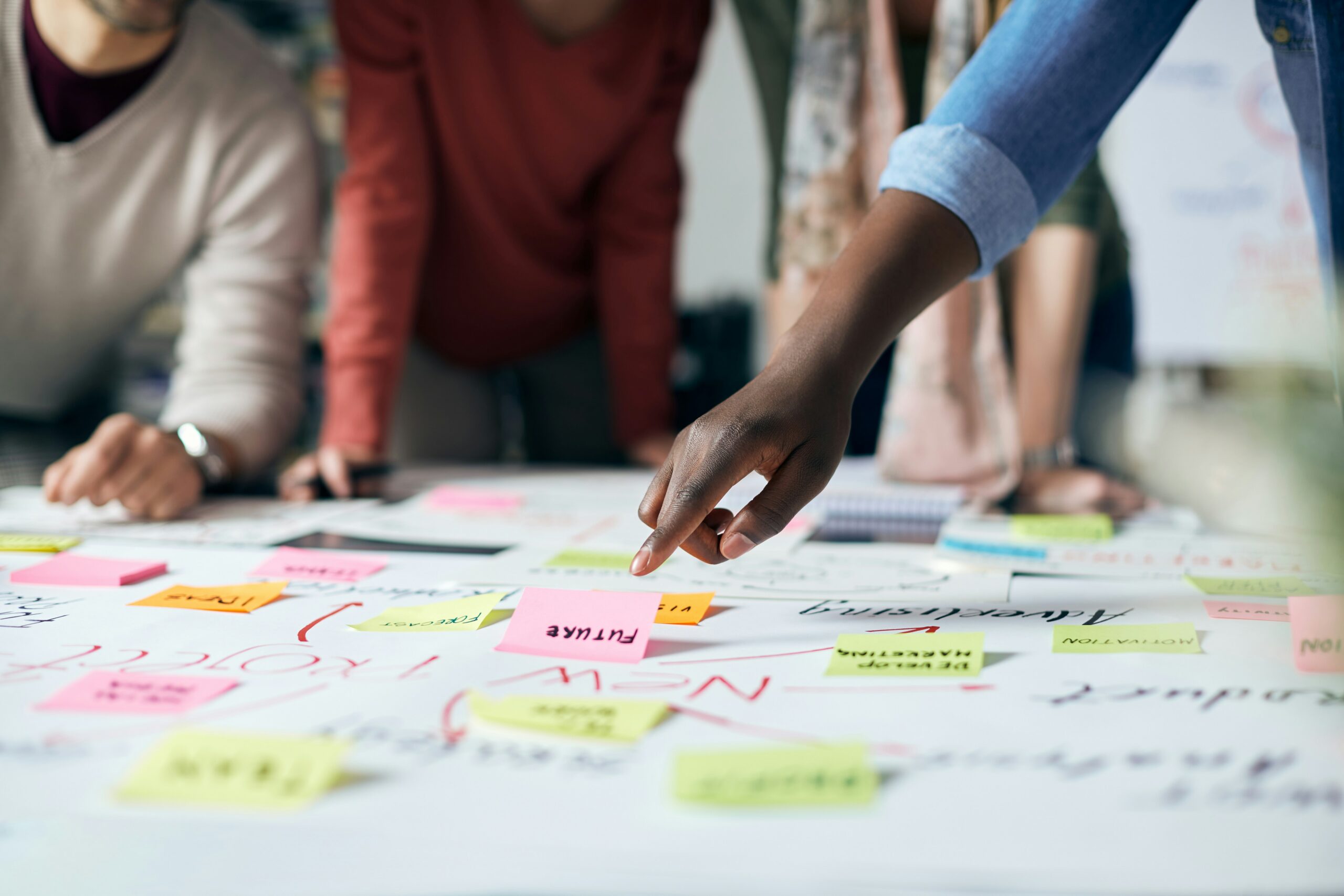 People gathered around table, some pointing to sticky notes on the table