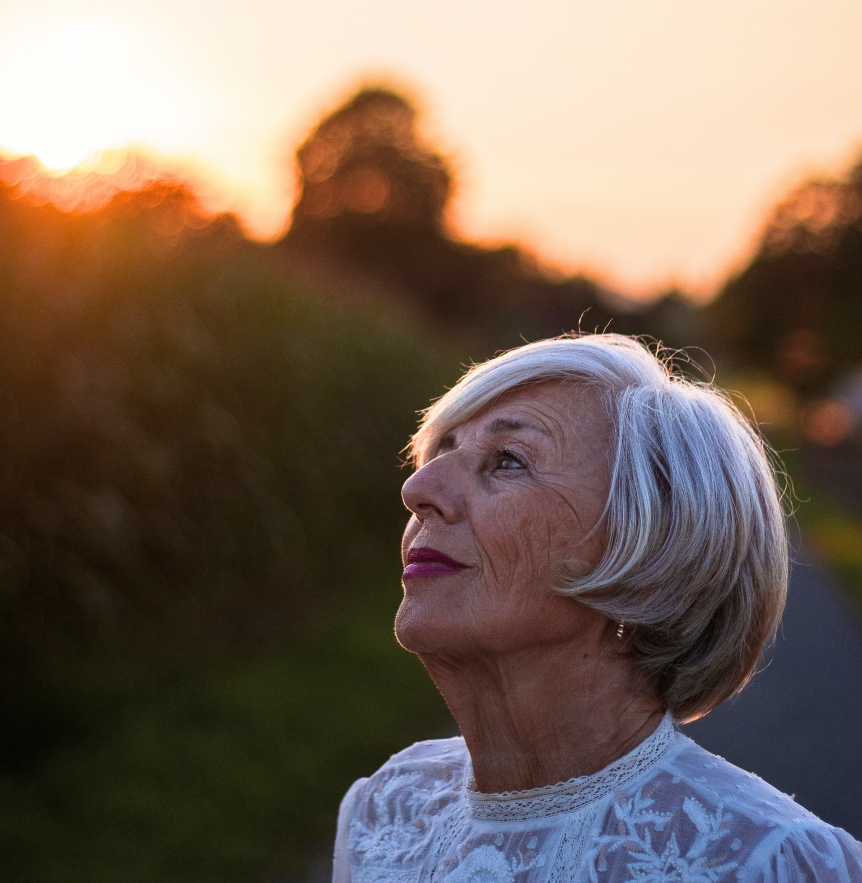 Woman looking up at sky, with sunset behind her.