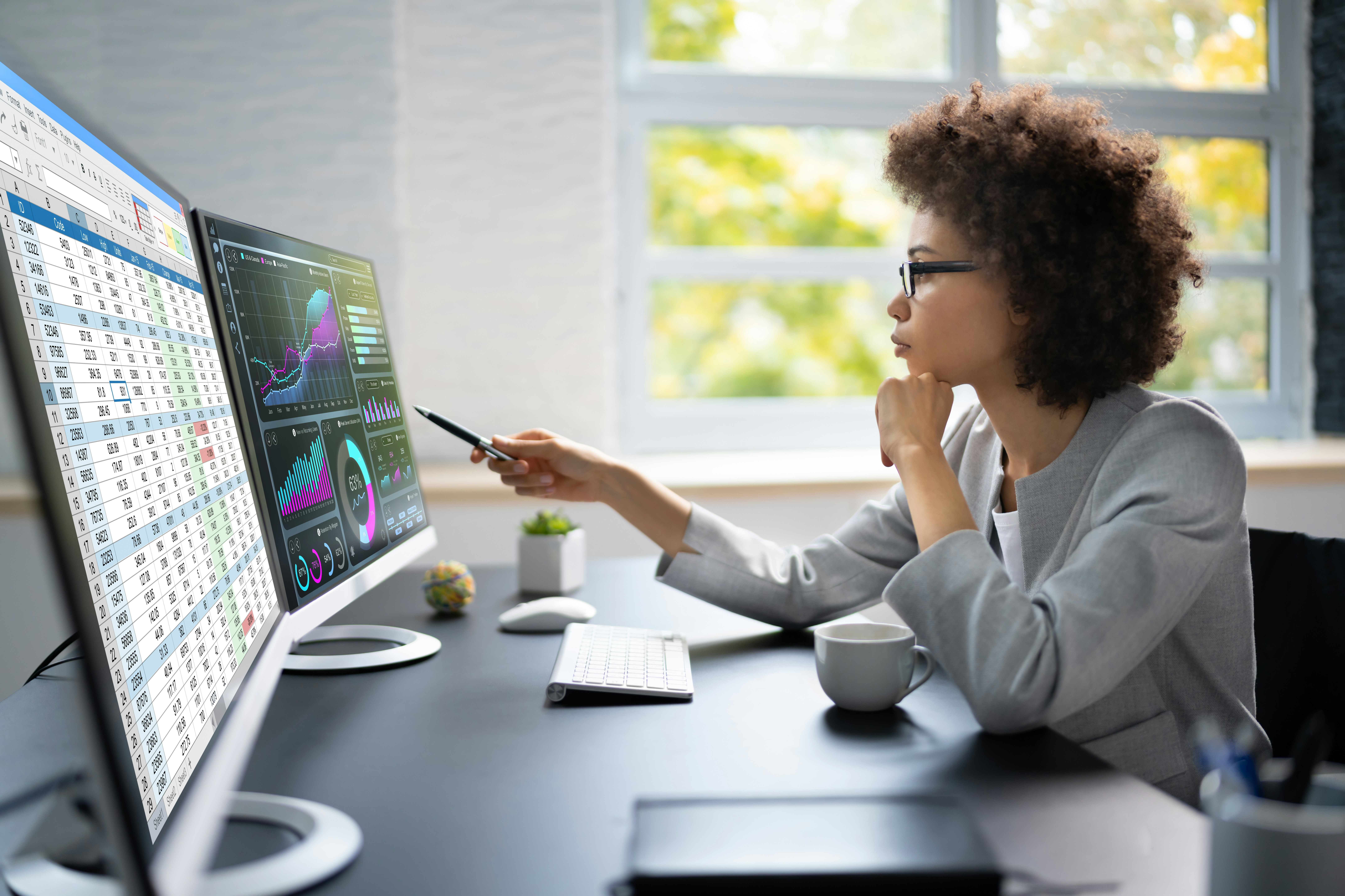 Woman analyzing data on two computer screens