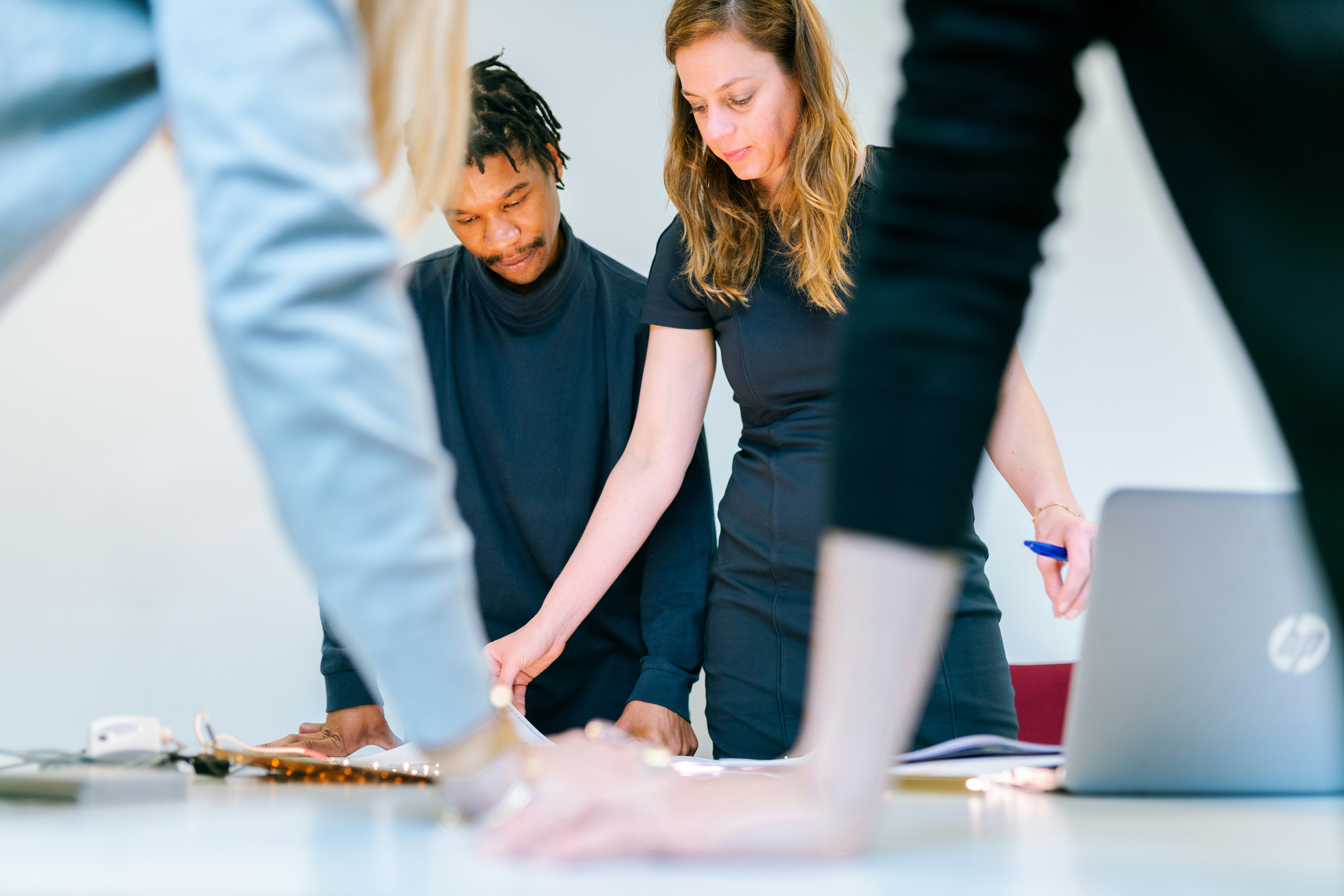 A group of people standing up and collaborating on a project around a table.