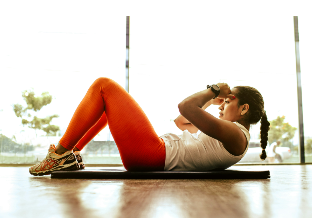 Woman doing sit-ups on a mat on the floor